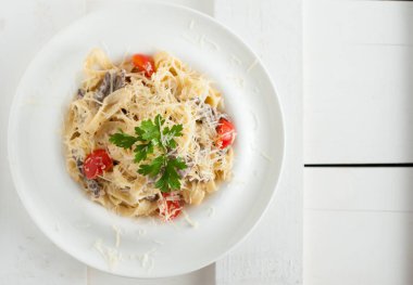 Beyaz bir tabak içinde mermer sığır eti ile makarna. Beyaz ahşap tahta masanın üzerine yerleştirilen