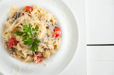 Beyaz bir tabak içinde mermer sığır eti ile makarna. Beyaz ahşap tahta masanın üzerine yerleştirilen