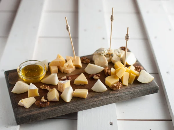 Peynir bal ve fındık ile çeşitli çeşitli. Bir koyu ahşap tahta üzerine yerleştirilmiş