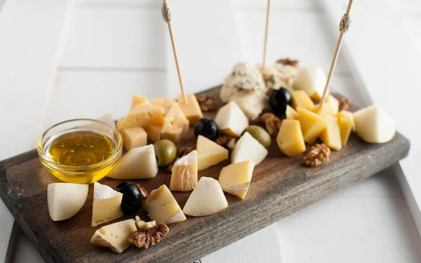 Variedad variada de quesos con miel y frutos secos. Colocado en un tablero de madera oscura —  Fotos de Stock