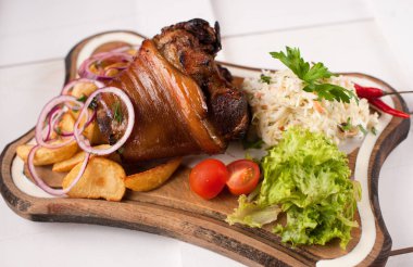 Lahana, patates, soğan ve yeşillik bir ahşap kesme tahtası üzerinde pişmiş domuz knuckle