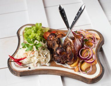 Lahana, patates, soğan ve yeşillik bir ahşap kesme tahtası üzerinde pişmiş domuz knuckle