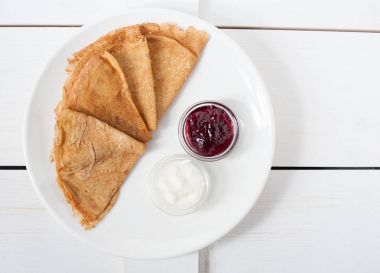 Beyaz bir tabak üzerinde geleneksel krep reçel ve krema ile servis