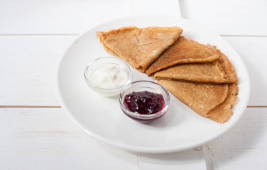 Beyaz bir tabak üzerinde geleneksel krep reçel ve krema ile servis
