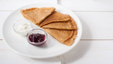 Beyaz bir tabak üzerinde geleneksel krep reçel ve krema ile servis