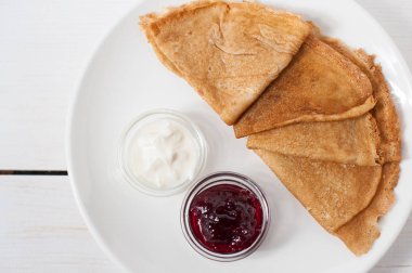 Beyaz bir tabak üzerinde geleneksel krep reçel ve krema ile servis