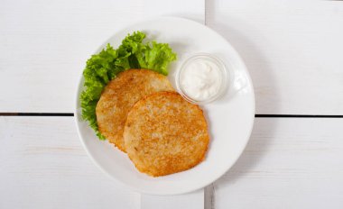 Ekşi krema ve taze yaprak salata beyaz tabakta ile kızarmış patates pancakes