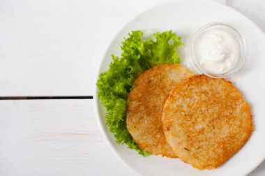 Ekşi krema ve taze yaprak salata beyaz tabakta ile kızarmış patates pancakes