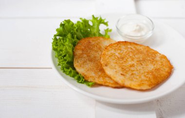 Ekşi krema ve taze yaprak salata beyaz tabakta ile kızarmış patates pancakes