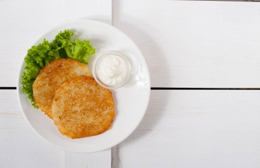 Ekşi krema ve taze yaprak salata beyaz tabakta ile kızarmış patates pancakes