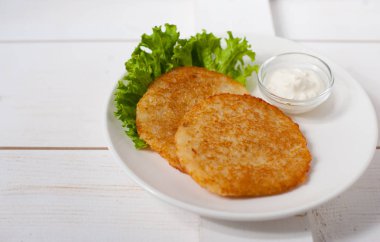 Ekşi krema ve taze yaprak salata beyaz tabakta ile kızarmış patates pancakes