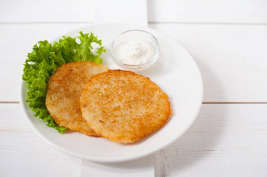 Ekşi krema ve taze yaprak salata beyaz tabakta ile kızarmış patates pancakes