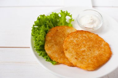 Ekşi krema ve taze yaprak salata beyaz tabakta ile kızarmış patates pancakes