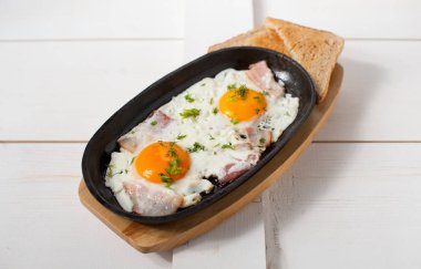 Omlet pastırma ve taze otlar ile bir tencerede kızartılır. Ekmek tost ile hizmet