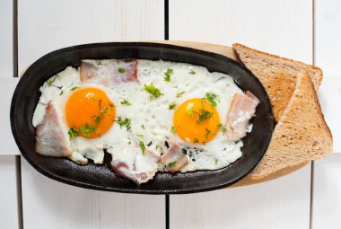 Omlet pastırma ve taze otlar ile bir tencerede kızartılır. Ekmek tost ile hizmet