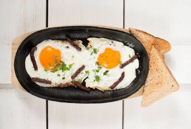 Omlet tütsülenmiş sosis ve taze otlar ile bir tencerede kızartılır. Ekmek tost ile hizmet