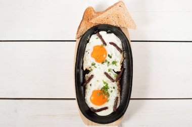 Omlet tütsülenmiş sosis ve taze otlar ile bir tencerede kızartılır. Ekmek tost ile hizmet