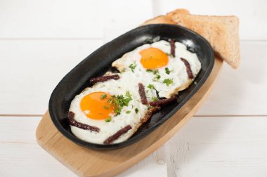 Omlet tütsülenmiş sosis ve taze otlar ile bir tencerede kızartılır. Ekmek tost ile hizmet