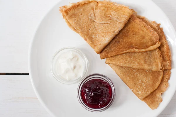 Beyaz bir tabak üzerinde geleneksel krep reçel ve krema ile servis