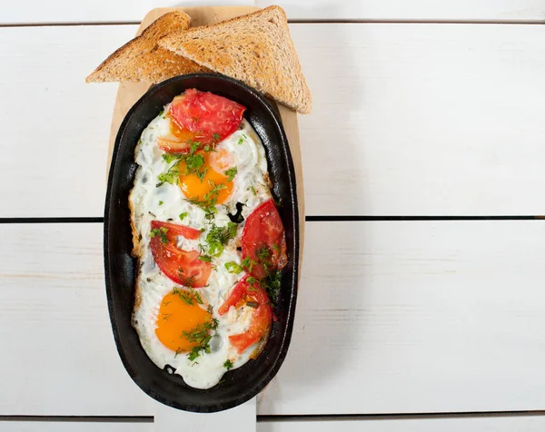 Sahanda yumurta taze domates ve taze otlar ile bir tencerede kızartılır. Ekmek tost ile hizmet