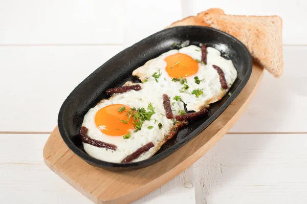 Omlet tütsülenmiş sosis ve taze otlar ile bir tencerede kızartılır. Ekmek tost ile hizmet