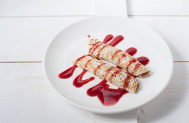 Beyaz bir plaka üzerinde sulu meyve ile doldurulmuş krep geleneksel reçel