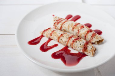 Beyaz bir plaka üzerinde sulu meyve ile doldurulmuş krep geleneksel reçel