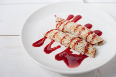 Beyaz bir plaka üzerinde sulu meyve ile doldurulmuş krep geleneksel reçel