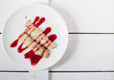 Beyaz bir plaka üzerinde sulu meyve ile doldurulmuş krep geleneksel reçel