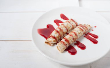 Beyaz bir plaka üzerinde sulu meyve ile doldurulmuş krep geleneksel reçel