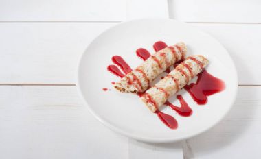 Beyaz bir plaka üzerinde sulu meyve ile doldurulmuş krep geleneksel reçel