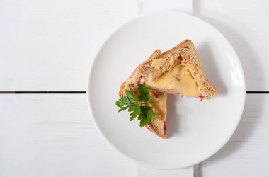 Peynir, domates, taze otlar ve vecinos beyaz bir tabak üzerinde iki sıcak sandviç