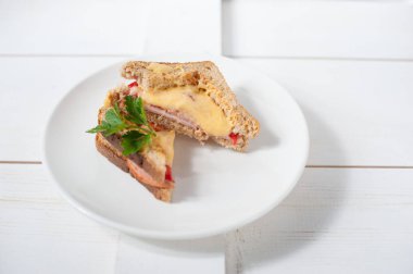 Peynir, domates, taze otlar ve vecinos beyaz bir tabak üzerinde iki sıcak sandviç