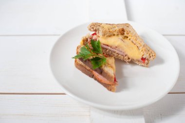 Peynir, domates, taze otlar ve vecinos beyaz bir tabak üzerinde iki sıcak sandviç