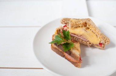 Peynir, domates, taze otlar ve vecinos beyaz bir tabak üzerinde iki sıcak sandviç