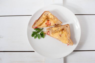 Peynir, domates, taze otlar ve vecinos beyaz bir tabak üzerinde iki sıcak sandviç