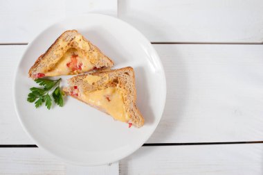 Peynir, domates, taze otlar ve vecinos beyaz bir tabak üzerinde iki sıcak sandviç