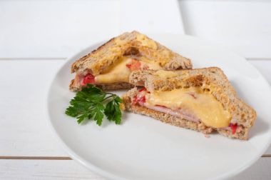 Peynir, domates, taze otlar ve vecinos beyaz bir tabak üzerinde iki sıcak sandviç