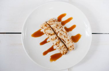 Geleneksel doldurulmuş krep beyaz tabakta karamel sos ile