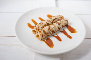 Geleneksel doldurulmuş krep beyaz tabakta karamel sos ile