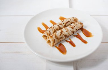 Geleneksel doldurulmuş krep beyaz tabakta karamel sos ile