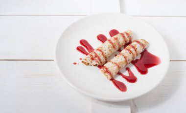 Beyaz bir plaka üzerinde sulu meyve ile doldurulmuş krep geleneksel reçel