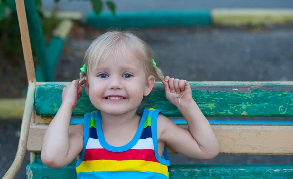Feliz menina loira européia de três anos sorrindo e segurando-se para tranças — Fotografia de Stock