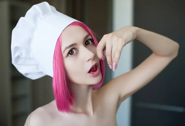 Emo fille aux cheveux roses dans un chapeau de chef manger une cerise — Photo