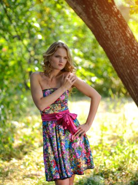 Yaz parkta poz parlak renkli elbiseli genç sarışın kız