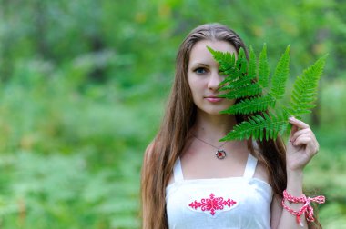 Uzun saçlı ve Slav etnik elbise genç güzel bir Slav kız onun yüz fern yaprakla kaplı