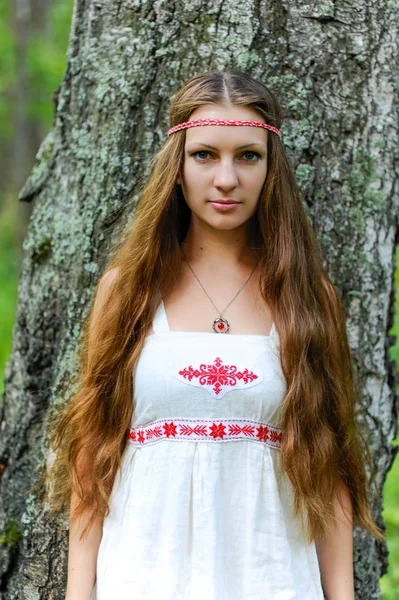 Portréja egy fiatal gyönyörű szláv hosszú hajú lány szláv etnikai ruha nyári erdőben — Stock Fotó