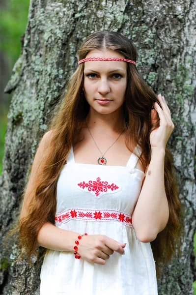 Портрет молодой красивой славянской девушки с длинными волосами и славянской этнической одеждой в летнем лесу — стоковое фото