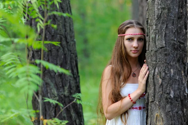 Retrato de uma jovem linda menina eslava com cabelos longos e vestido étnico eslavo em uma floresta de verão — Fotografia de Stock