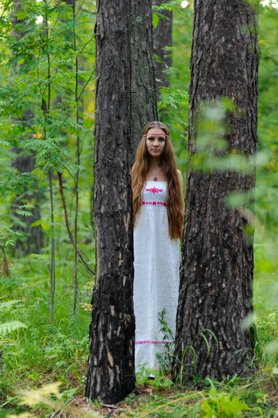 Портрет молодой красивой славянской девушки с длинными волосами и славянской этнической одеждой в летнем лесу — стоковое фото